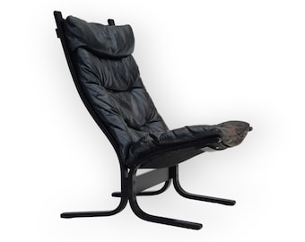 May include: A black leather armchair with a curved wooden frame and a padded seat and back. The chair has a unique design with a low profile and a wide, comfortable seat.