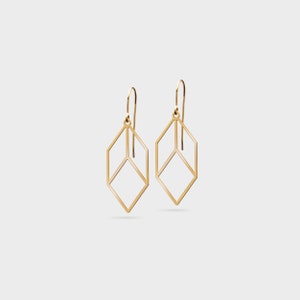 Peut inclure: Une paire de boucles d'oreilles pendantes géométriques dorées avec un design en forme de cube.