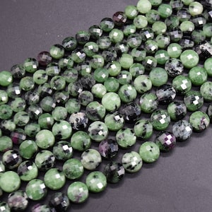 May include: A strand of green and black gemstone beads. The beads are round and faceted, with a polished finish.