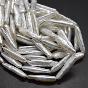 May include: A strand of white freshwater rice pearls, each pearl is long and slender, with an iridescent sheen.