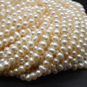 May include: A close-up of a strand of white freshwater pearls. The pearls are round and smooth, with a slight iridescent sheen.