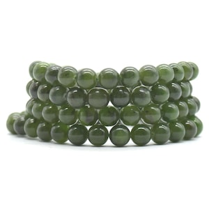 May include: A stack of jade green beaded bracelets. The beads are round and polished. The bracelets are a deep, forest green colour and are displayed against a white background. Each bead is approximately 1 cm in diameter.