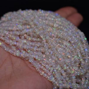 May include: A strand of white opal gemstone beads. The beads are small and irregular in shape, with a slight iridescent shimmer.
