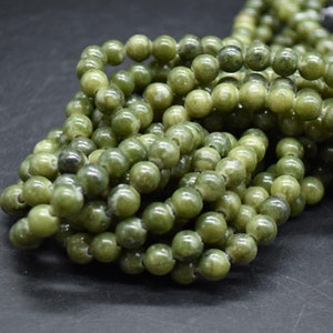 Könnte beinhalten: Eine Schnur aus grünen Jadeperlen, jede Perle ist rund und glatt. Die Perlen sind auf einem durchsichtigen Faden aufgereiht.