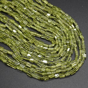 May include: A strand of light green peridot beads, each bead is faceted and has a rectangular shape.