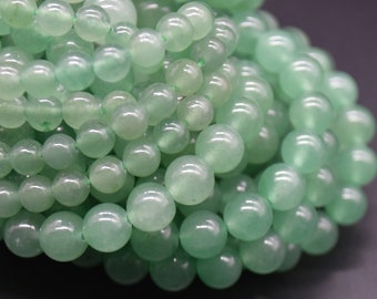 Op de afbeelding: Een streng lichtgroene jade kralen. De kralen zijn rond en glad en zijn geregen aan een doorzichtige draad.