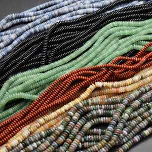 May include: Multiple strands of small, flat, round disc-shaped beads in various colours including light blue, black, light green, reddish-brown, cream, and a multi-coloured speckled pattern. The beads are arranged in parallel rows across the frame.