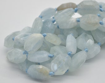 May include: A strand of light blue aquamarine beads, each bead is faceted and oval shaped. The beads are strung on a thin blue cord.