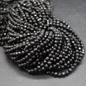 May include: A strand of black faceted gemstone beads. The beads are round and have a shiny, polished finish.