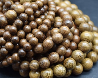 May include: A close-up of a pile of dark brown wooden beads with a striped pattern. The beads are round and smooth, and they are arranged in a random pattern.