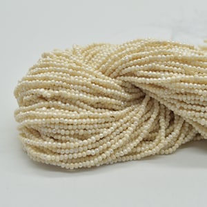 Può includere: Un filo di piccole perle d'acqua dolce rotonde di colore bianco crema. Le perle sono di dimensioni uniformi e hanno un leggero bagliore iridescente.