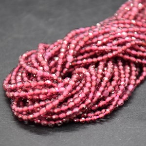 Op de afbeelding: Een streng roze gefacete glazen kralen. De kralen zijn klein en rond en hebben een glanzende, iriserende afwerking.