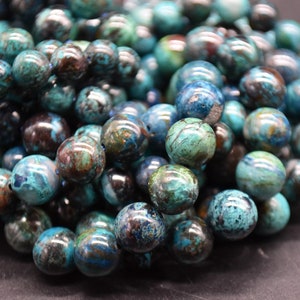 Peut inclure: Gros plan sur un brin de perles rondes en pierre précieuse bleu-vert avec des marbrures brunes et noires. Les perles sont lisses et polies.