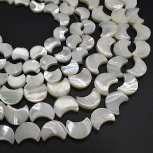 Può includere: Una collana di perline di conchiglia a forma di mezza luna bianche iridescenti. Le perline sono infilate su un filo bianco sottile.