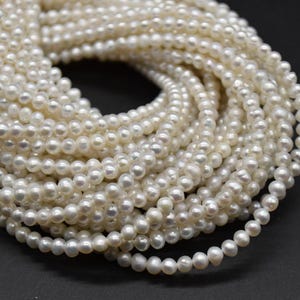 May include: A close-up of several strands of white pearls. The pearls are small, round, and have a shiny surface. The strands are arranged in a circular pattern, creating a sense of depth and texture. The background is a dark, solid colour.