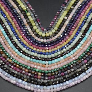 Może przedstawiać: Asortyment koralików z kamieni szlachetnych w różnych kolorach, w tym niebieskim, zielonym, różowym i fioletowym. Korale są fasetowane i mają kwadratowy kształt.