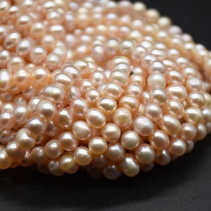 May include: A strand of pink freshwater pearls. The pearls are round and have a smooth, lustrous finish.
