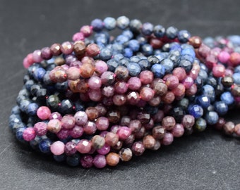 May include: A collection of faceted gemstone beads in shades of blue, pink, and brown. The beads are strung together, creating a textured and colorful display. The gemstones are round and appear to be polished.