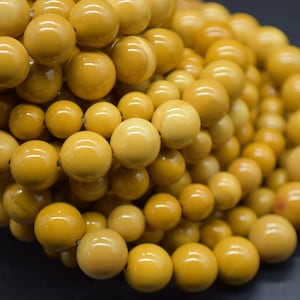 May include: A close-up of a pile of round, yellow beads. The beads are smooth and shiny, and they are all about the same size.