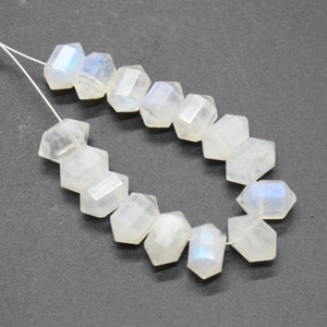 May include: A strand of white moonstone beads with a faceted, hexagonal shape. The beads are strung on a thin wire and have a subtle iridescent sheen.