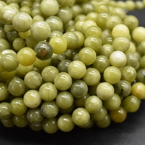 May include: A strand of round, green and yellow jade beads. The beads are smooth and polished, and they have a natural, earthy look.