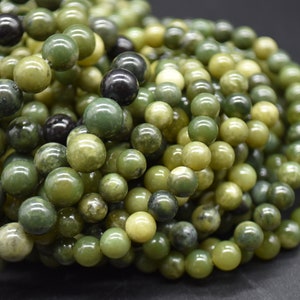 May include: A close-up of a pile of green and black jade beads. The beads are round and smooth, and they have a natural, earthy look.