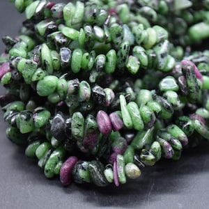 May include: A strand of green, black, and pink gemstone chips. The chips are irregularly shaped and have a glossy finish.