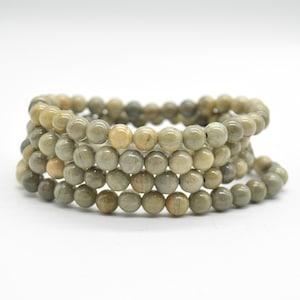 Op de afbeelding: Een stapel groene en bruine edelsteen kralen armbanden. De kralen zijn rond en hebben een gladde, gepolijste afwerking.