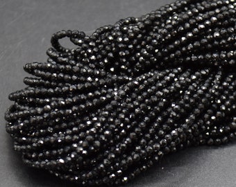 May include: A strand of black faceted gemstone beads. The beads are small and round, and they have a shiny, polished finish.