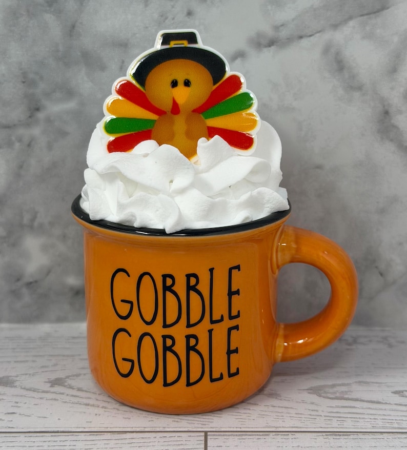 May include: A white ceramic mug with a black handle and the text "But first, coffee" in a handwritten style. The mug is on a white surface. The mug is likely for hot beverages.