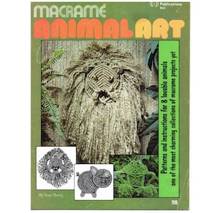 May include: A book cover with the title "Macrame Animal Art" in orange and yellow letters. The cover features a macrame lion, a macrame pig, and a macrame frog. The book is green and has the text "Patterns and instructions for 8 lovable animals one of the most charming collections of macrame projects yet" on the right side.