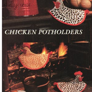 May include: Three knitted chicken pot holders. One is black and white with a red comb, one is tan with a red comb, and one is black and white with a red comb. The pot holders are in front of a fireplace with a pot on the hearth.