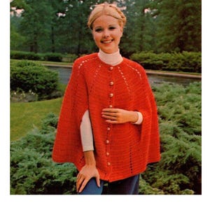 Puede incluir: Una capa de crochet roja con cierre de botón. La capa tiene un escote festoneado y un ajuste holgado.