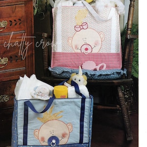 May include: Two quilted nappy bags, one pink with a baby girl design and one blue with a baby boy design. Both bags are filled with baby supplies.
