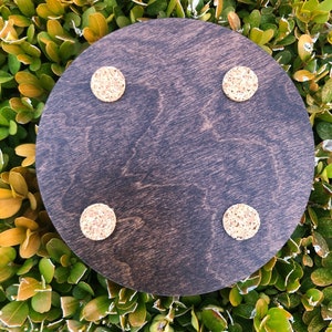 May include: A dark brown round wooden coaster with four cork circles attached to the bottom.