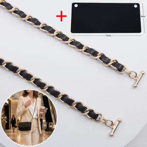 May include: A gold-tone metal chain strap interwoven with black leather-like material, featuring toggle ends. Includes a black rectangular base measuring 17 inches by 8 inches, and an inset showing the strap attached to a quilted handbag.