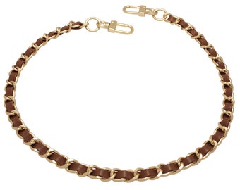 May include: A brown leather and gold chain handbag strap. The strap is made of a woven leather and metal chain.