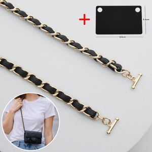 May include: A gold-tone metal chain strap interwoven with black leather-like material, featuring toggle bar ends. Includes a black rectangular plate measuring 8.5 cm by 5.4 cm. The strap is shown attached to a small black quilted bag.