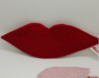 May include: Two felt lips, one red and one pink, with a white tag attached to each. The tag on the red lips says "Heiß" and the tag on the pink lips says "Kein".
