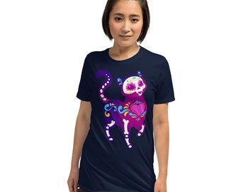 Könnte beinhalten: Ein marineblaues T-Shirt mit einem lila und pinkfarbenen Katzenskelett-Design. Die Katze hat ein Zucker Schädel Gesicht mit floralen Details.