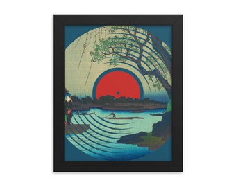 Puede incluir: Una impresión enmarcada de una imagen de estilo japonés de grabado en madera de un sol rojo que sale sobre un río con un árbol y una persona en un bote. La imagen está estilizada para parecerse a un disco de vinilo.