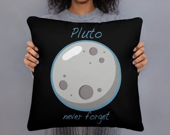 Op de afbeelding: Zwart vierkant kussen met een cartoon illustratie van Pluto, een grijze planeet met kraters, omlijnd in blauw. De tekst "Pluto" staat boven de planeet en "never forget" eronder, beide in lichtblauw.
