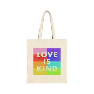 Könnte beinhalten: Eine beige Tragetasche mit einem farbenfrohen Grafikdesign, auf dem "LOVE IS KIND" steht. Die Grafik besteht aus Quadraten in den Farben Rosa, Lila, Rot, Orange, Gelb, Grün und Blau.