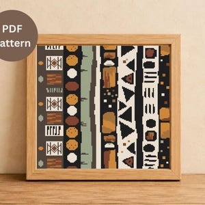 May include: A framed PDF pattern featuring a colorful, geometric design. The pattern includes vertical stripes with various shapes and colors, including brown, black, white, and orange. The frame is made of light-colored wood, and the text "PDF Pattern" is visible.