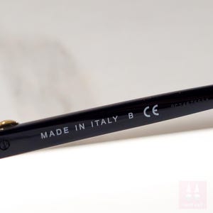 Puede incluir: Primer plano de una patilla de gafas negra. El texto "MADE IN ITALY" est&aacute; impreso en blanco. La montura tambi&eacute;n tiene las letras "B" y "CE" impresas. La montura es de dise&ntilde;o elegante y moderno.