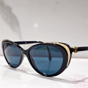 Puede incluir: Gafas de sol negras con forma de ojo de gato y lentes azules. Las monturas tienen detalles dorados y un dise&ntilde;o estampado en los laterales. Un accesorio elegante.