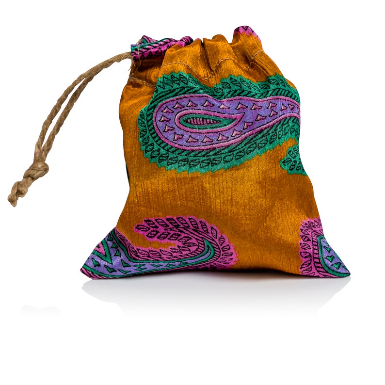 May include: A small, orange drawstring bag with a paisley pattern in shades of pink, green, and purple. The bag is made of a soft, silky fabric and has a drawstring closure.