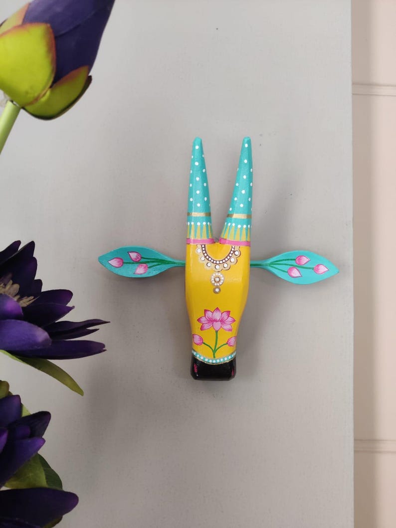 Pode incluir: Cabe&ccedil;a de vaca de madeira pintada &agrave; m&atilde;o, amarela, com chifres turquesa e detalhes rosa e turquesa. A cabe&ccedil;a de vaca apresenta um design floral e &eacute; montada na parede. &Eacute; um objeto decorativo.