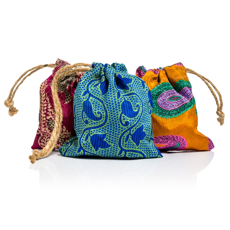 May include: Three colorful drawstring bags with different patterns. The bag on the left is pink and red with a floral design. The middle bag is blue with a green floral design. The bag on the right is orange with a paisley design.