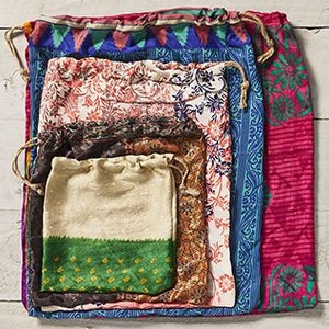 May include: Set of five colorful fabric drawstring bags, nested inside each other. The bags are made from recycled saris and feature various floral and geometric patterns.